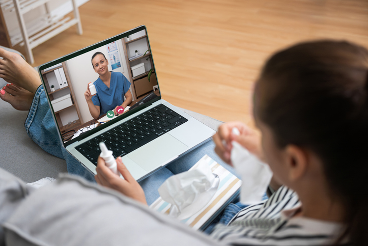 Patient on a laptop telehealth call with a clinician from home